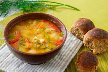 Portion of vegetable soup with lentils and homemade bread in a clay plate