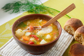 Portion of vegetable soup with lentils and homemade bread in a clay plate