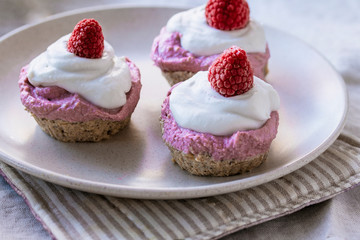 homemade cake with raw strawberries and cashew cream on almond nut dough, healthy vegan food concept. close up