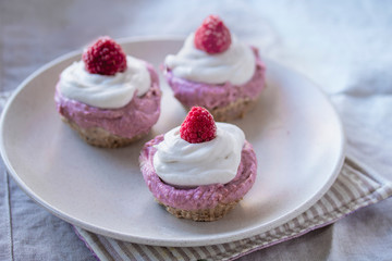 homemade cake with raw strawberries and cashew cream on almond nut dough, healthy vegan food concept. close up