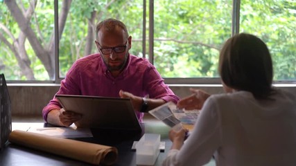 Creative couple arguing over print design by the table at home office