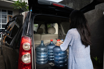 woman carrying a gallon of water put in car trunk