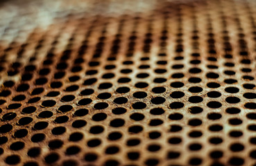 Perforated brown rusty iron sheet texture. Surface of industrial mesh with depth of field....