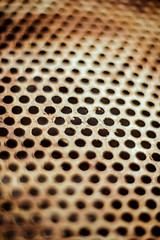 Perforated brown rusty iron sheet texture. Surface with depth of field, abstract industrial mesh. Vertical light background