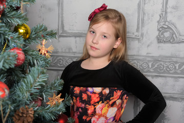 girl blonde child in black with red dress in christmas by the christmas tree