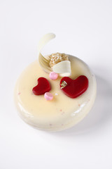 Contemporary Layered Yogurt Mousse Cake decorated with Strawberry Jelly Hearts, on white background.
