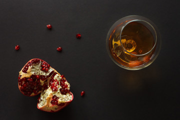 A glass of cognac and pomegranate. Still life. View from the top. Dark background