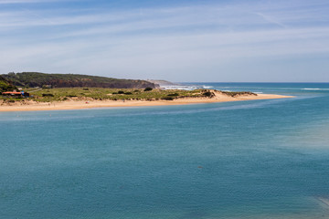 Long sandy beach with some cliffs in the distance. Beach on the confluence of Mira river into...