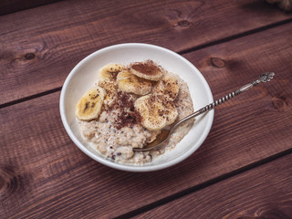 Oatmeal with banana slices, sprinkled with chocolate chips on a wooden tray