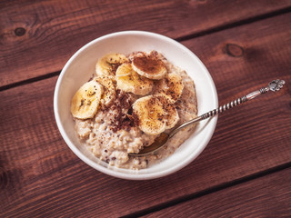 Healthy breakfast of oatmeal, banana slices and chocolate chips are delicious porridge supplements. Blurred focus.