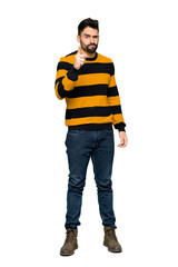 Fototapeta premium Full-length shot of Handsome man with striped sweater frustrated by a bad situation and pointing to the front on isolated white background