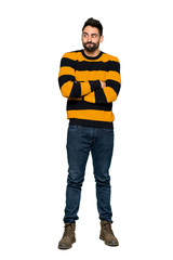 Full-length shot of Handsome man with striped sweater making doubts gesture while lifting the shoulders on isolated white background