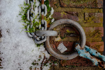 Rusty metal chain on the brick’s pavement
