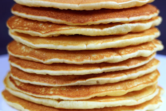 Stack of homemade plain pancakes served on white plate 