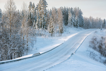 Fototapeta na wymiar Snowy road winding through winter forest landscape in Eastern Finland