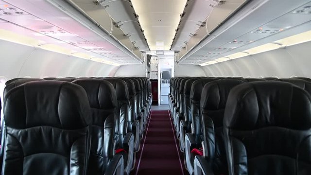 4K Interior of commercial airplane cabin with black and red passenger seats.