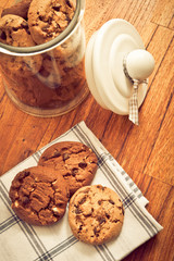 home made chocolate chips cookies biscuits in a glass jar in rustic style 