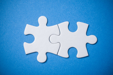 Closeup of Two connected jigsaw puzzle pieces on blue  background. The concept of finding the right solutions in teamwork.