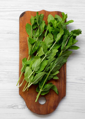 Fresh mint on rustic wooden board over white wooden surface, top view. Flat lay, overhead, from above.