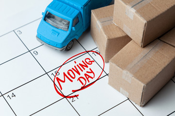 Moving day on the calendar is written in red. Calendar with a note with cardboard boxes and truck.