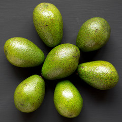 Whole avocados on black wooden surface, top view. Overhead, from above.