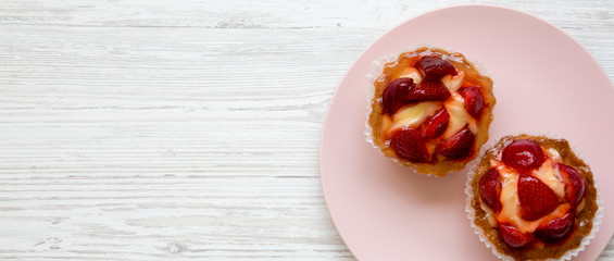 Strawberry vanilla cream cheese tarts on pink plate, top view. Overhead. Space for text.