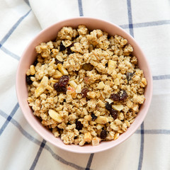 Pink bowl of fruit granola on cloth, top view. From above, overhead. Closeup.