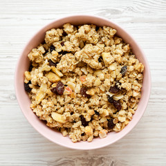 Pink bowl of fruit granola over white wooden table, top view. Overhead, from above. Close-up.