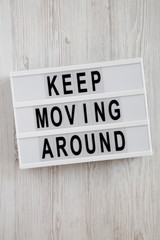 'Keep moving around' words on modern board over white wooden background, top view. From above, flat lay, overhead.