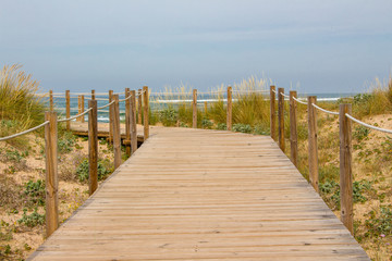 Wooden boardwalk on a sandy beach leading toward the ocean