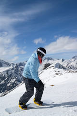 Fototapeta na wymiar Snowboarder downhill on snowy ski slope in high mountains