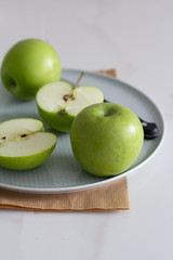 green apples on a plate with a knife.