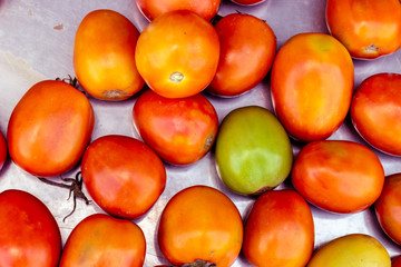 The fresh tomatoes on a tray for sale in the bazaar.