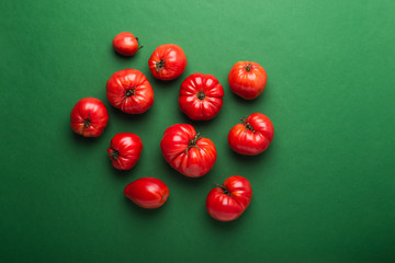 Fresh ripe tomatoes on green background, top view