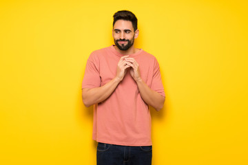 Handsome man over yellow wall scheming something