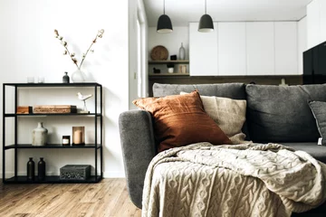 Fotobehang Per kamer Modern Nordic Scandinavian interior design. Bright open space living room with comfortable couch, knitted plaid, ginger pillow, kitchen, wooden floor. Elegant apartment for rent concept.  © Floral Deco