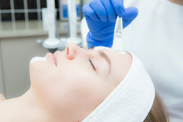 cosmetologist applying mask to young beautiful woman in spa