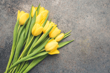 A bouquet of fresh, beautiful tulips arranged on dark moody background. Composition with yellow flowers. Romantic frame with free, copy space.