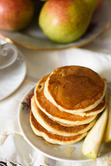 Fresh baked pancakes with honey, pear and tea closeup