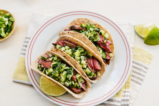 Steak tacos with green salsa and lime