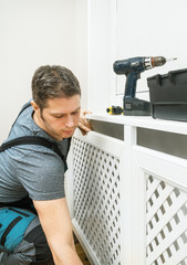 Fototapeta na wymiar Professional handyman assembling radiator cabinet at home.
