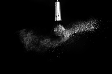 Cosmetic brush with white cosmetic powder spreading for makeup artist or graphic design in black background
