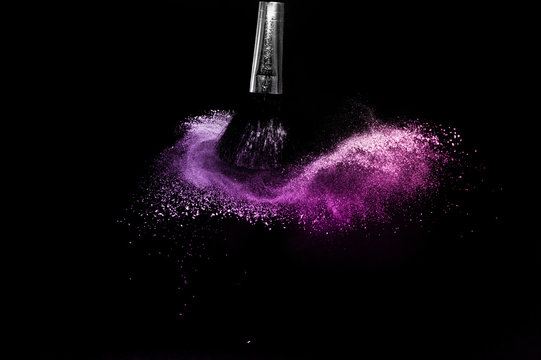 Cosmetic brush with purple cosmetic powder spreading for makeup artist and graphic design in black background