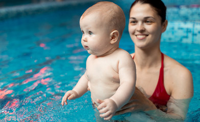 baby with mom learns to swim in the pool