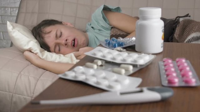 Sick child coughs. Sick little girl coughs while lying in bed.