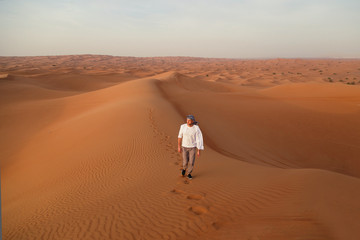 Man walking alone in the sunny desert near Dubai