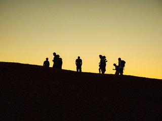 Fototapeta na wymiar Silhouettes of people atop Spitzkoppe, rock formations during sunset, Namibia.. Africa.