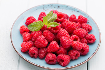 Fresh raspberries in a plate on a  vintage background.