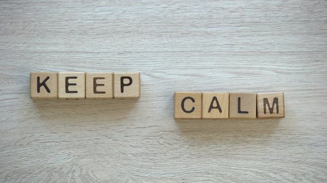 Keep calm, hands pushing words on wooden cubes, positive thinking and motivation