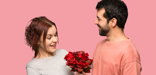 Couple in valentine day with flowers over isolated pink background